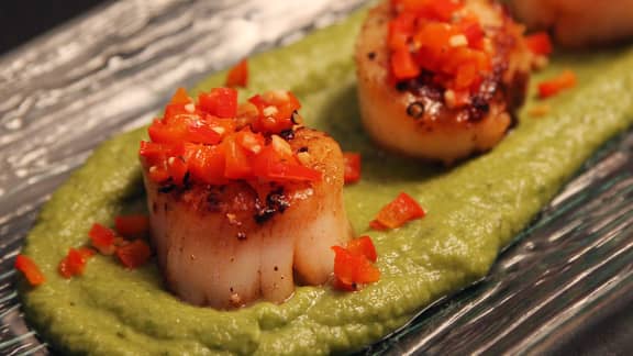Jetons de pétoncles poêlés sur tapis de purée de pois vert et dés de poivron rouge
